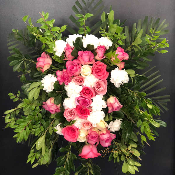 Pink and white rose funeral spray with lush greenery