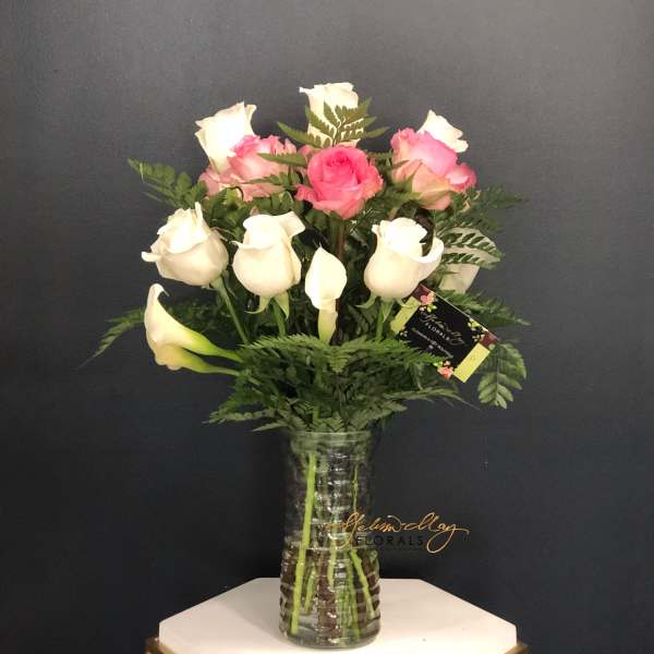 Pink and white roses arranged in a clear glass vase
