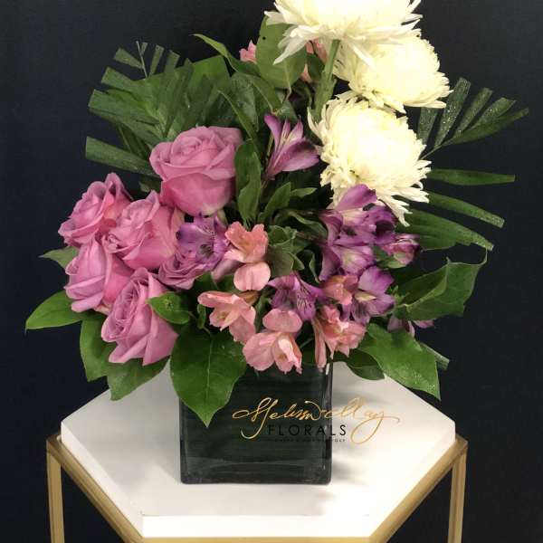 Pink roses and purple flowers in a black vase with white blooms
