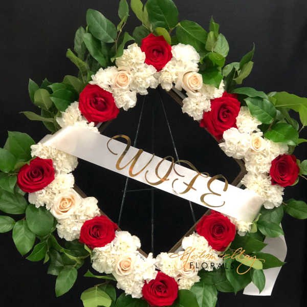 Heart-shaped floral wreath with red and white roses and a "WIFE" ribbon