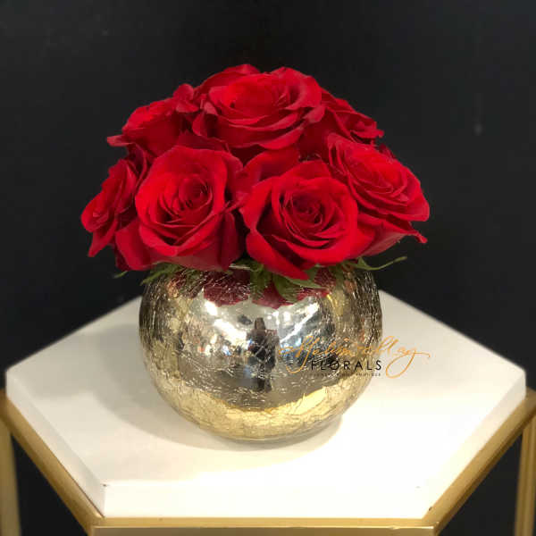 Red roses arranged in a gold mirrored vase