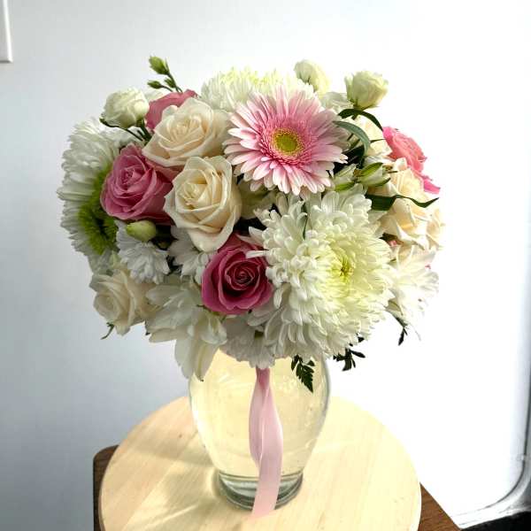 Pink and white mixed bouquet in a glass vase with a pink ribbon