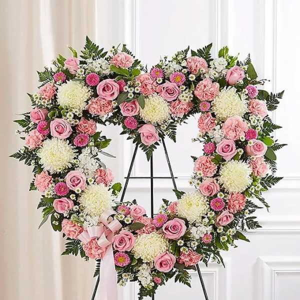 Heart-shaped floral wreath with pink and white flowers on a stand