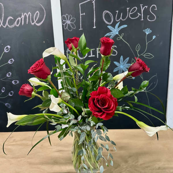 Red roses and white calla lilies in a clear glass vase
