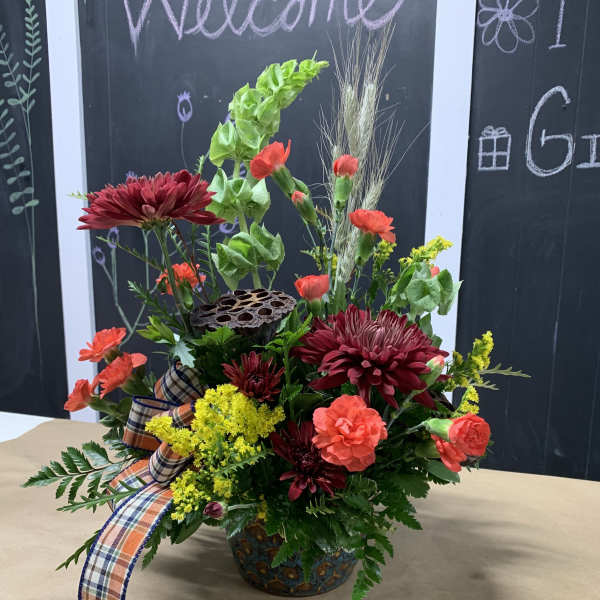 Mixed floral arrangement in a decorative vase with a plaid ribbon