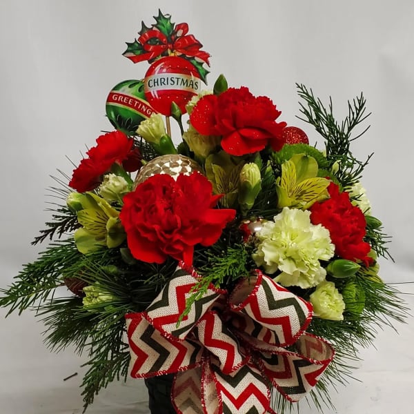 Christmas bouquet with red and white carnations, ornaments, and a chevron ribbon in a black container