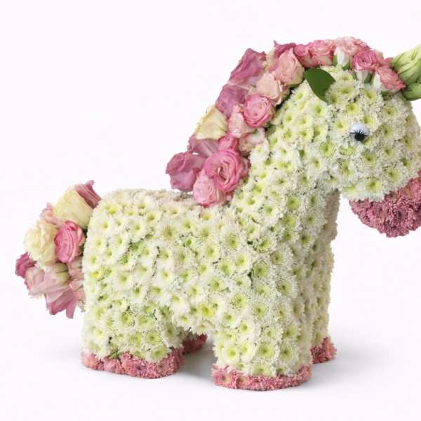 Flower-covered horse sculpture with pink roses and white blooms