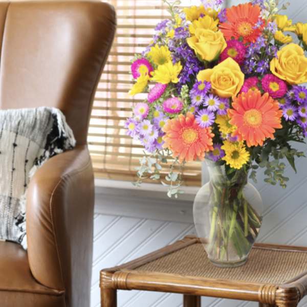 Colorful mixed bouquet in a clear glass vase on a side table
