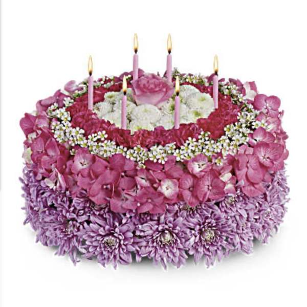 Round pink and purple floral cake with lit candles