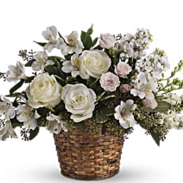 White roses and pale flowers in a woven basket