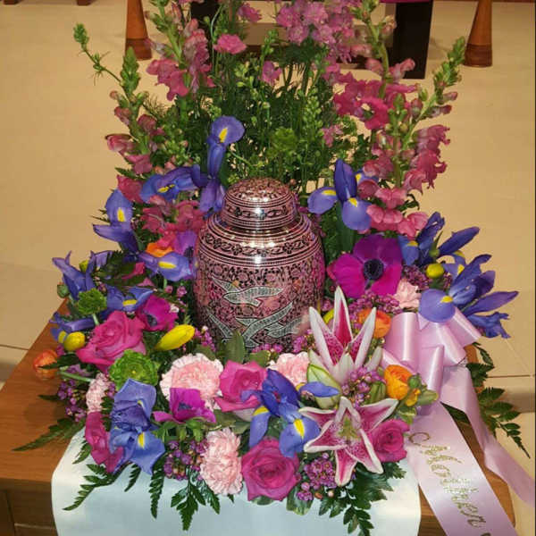 Colorful floral arrangement around a decorative urn in a church setting