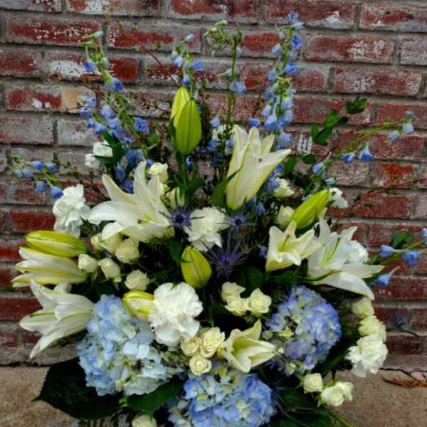 White lilies and blue hydrangeas in a white vase