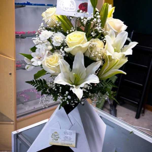 Bouquet of white lilies and roses with baby's breath in white wrap