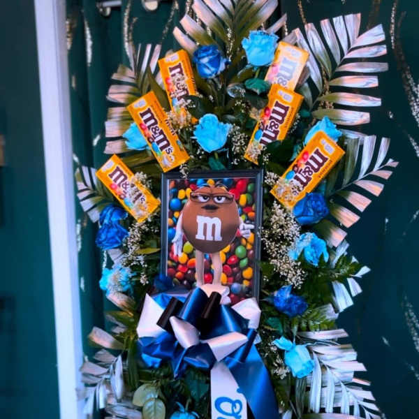 M&M-themed standing floral wreath with blue roses and candy bars