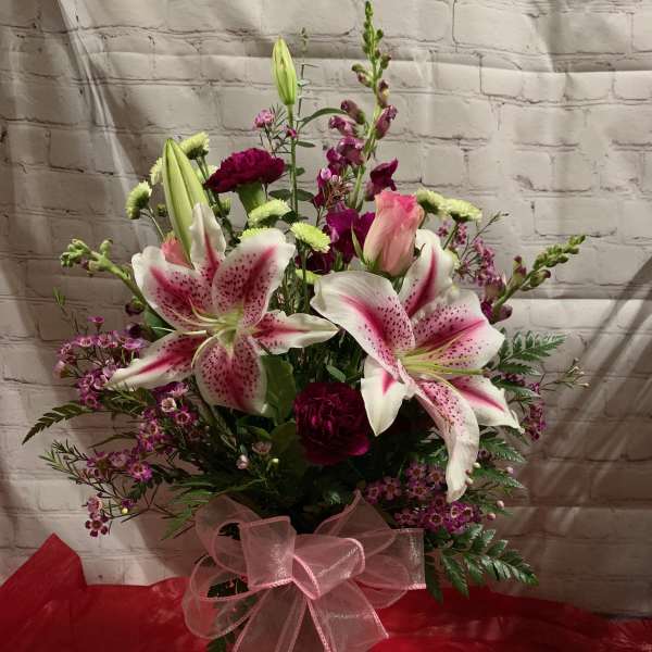 Pink and white lily bouquet in a vase with a pink ribbon