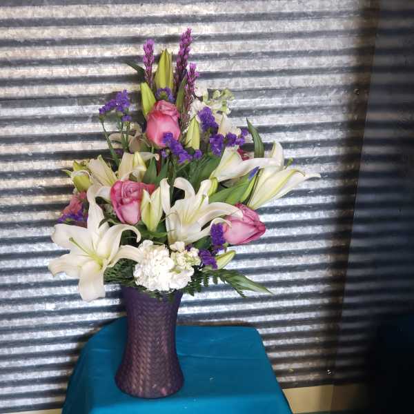 Pink roses and white lilies arranged in a purple vase
