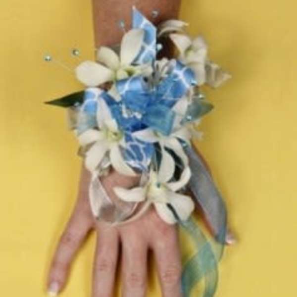 White flower corsage with blue ribbon on a hand