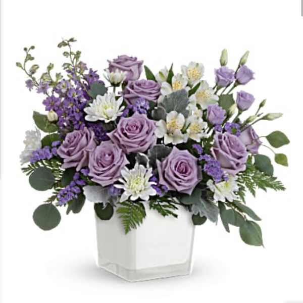 Lavender roses and white flowers in a clear square vase