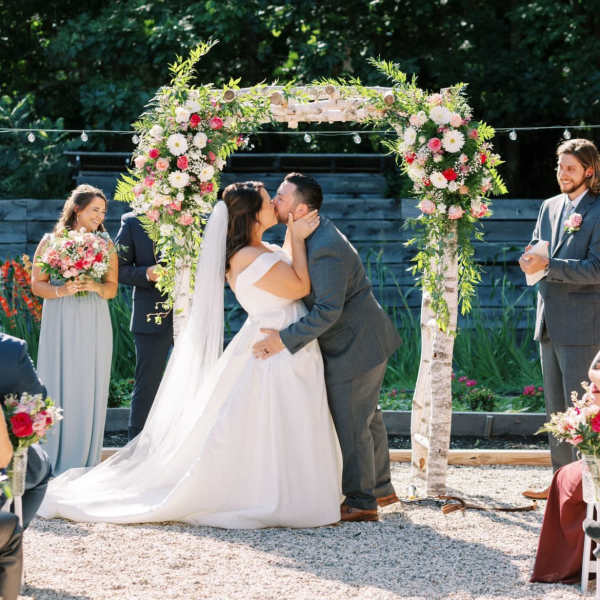 Bride and groom kissing under a floral wedding arch