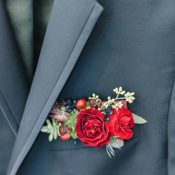 Red floral boutonniere pinned to a dark suit jacket