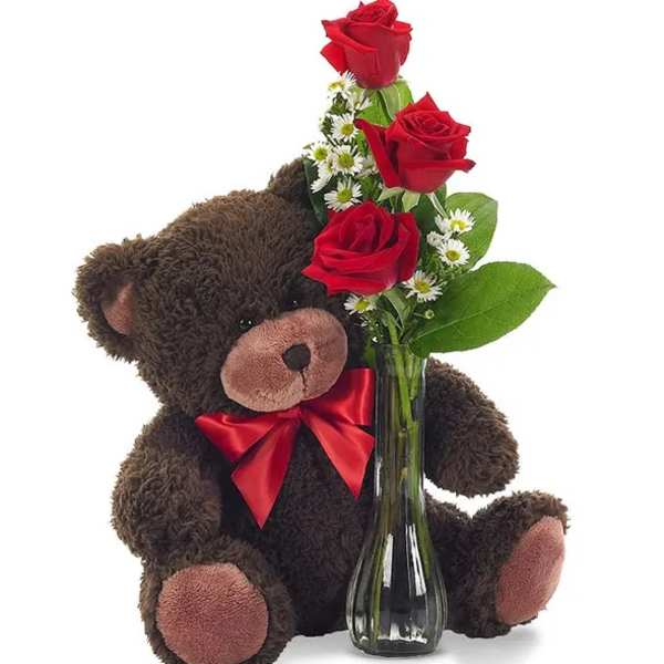 Teddy bear holding a vase of red roses and small white flowers