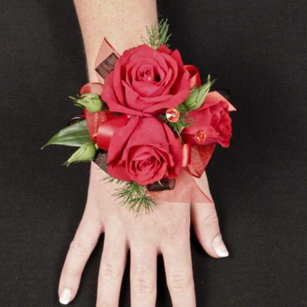 Red rose wrist corsage with ribbon on a person's wrist