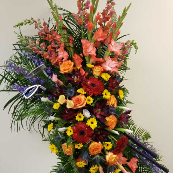 Tall standing floral spray with orange, red, yellow, and purple flowers