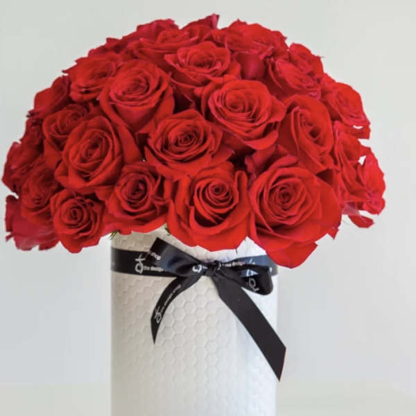 Red rose bouquet in a white vase with a black ribbon