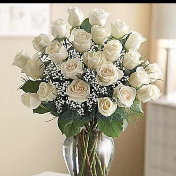 Arrangement of ivory roses with baby's breath in a clear glass vase