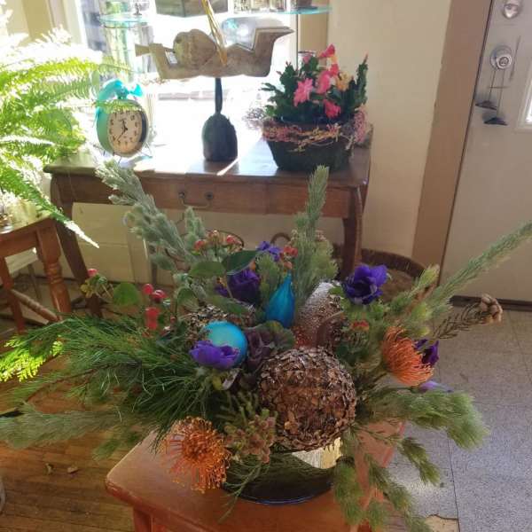 Low floral arrangement with purple and orange blooms in a dark container