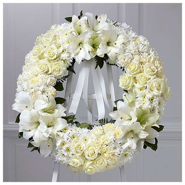 White floral wreath with roses and lilies on a stand