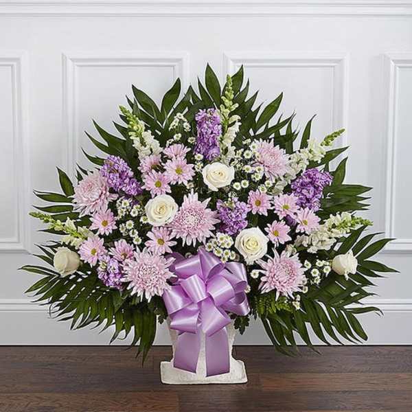 Lavender and white floral arrangement with a purple ribbon in a white vase