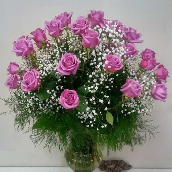 Pink roses arranged in a green glass vase with white baby's breath
