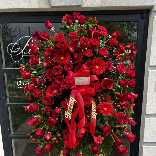 Large red sympathy standing spray with roses and gerbera daisies on an easel