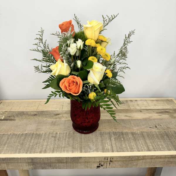 Mixed roses and yellow flowers in a red glass vase