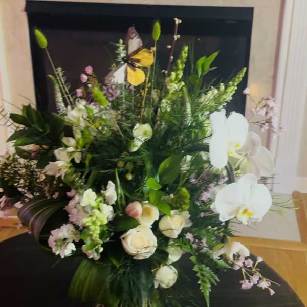 Large floral arrangement with white orchids, roses, and mixed greenery