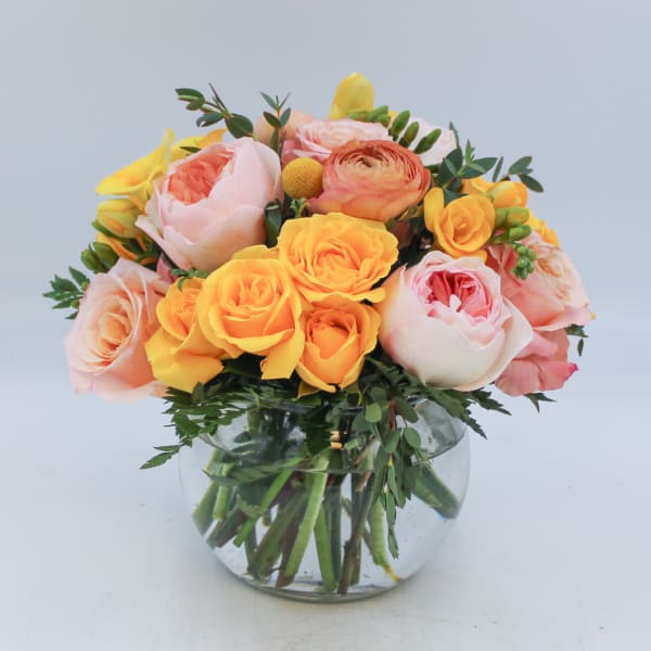 Bouquet of peach, pink, and yellow roses in a clear glass vase