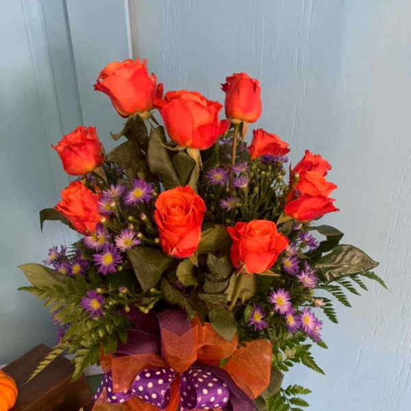 Orange roses and purple daisies in a ribboned bouquet