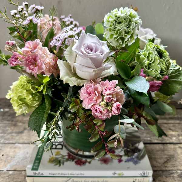 Mixed pink and green floral arrangement in a vase with a pale lavender rose