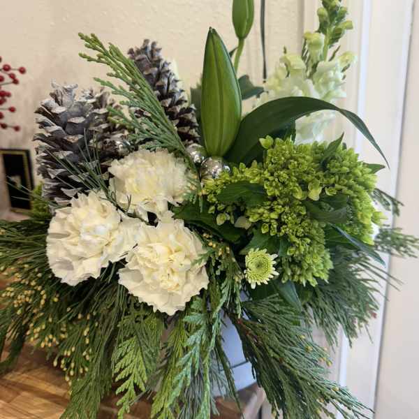 Holiday floral arrangement with white blooms, green flowers, and pinecones