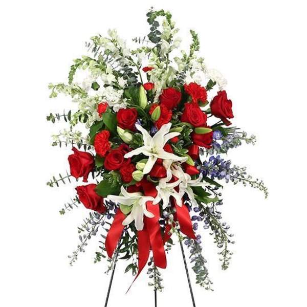 Standing floral spray with red roses, white lilies, and a red ribbon