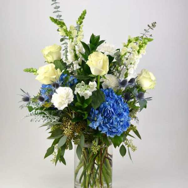 Blue and white floral arrangement in a clear glass vase