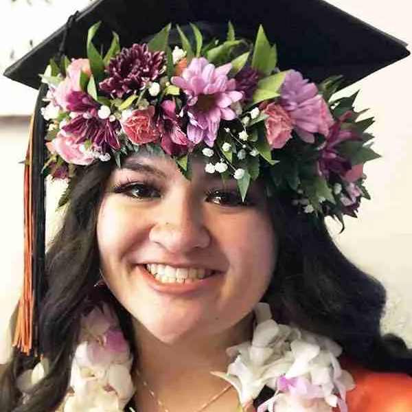 Woman wearing a graduation cap with a flower crown and lei