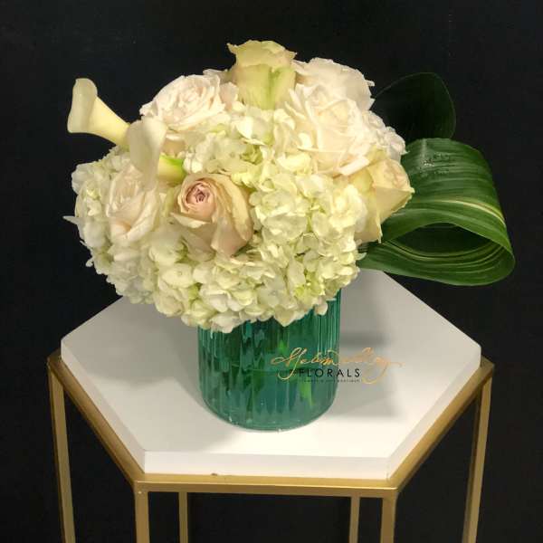Cream rose and hydrangea arrangement in a green glass vase