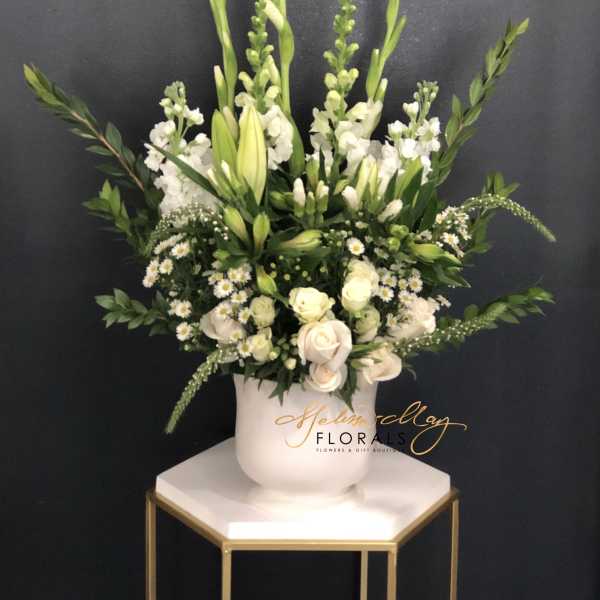 White floral arrangement in a white vase with tall green stems