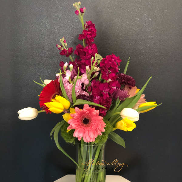 Mixed bouquet of pink, red, yellow, and white flowers in a glass vase