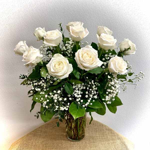 White roses arranged in a clear glass vase with baby's breath