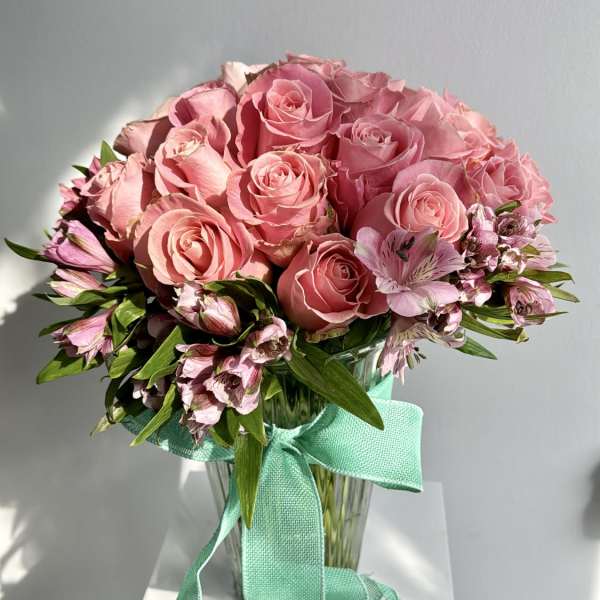 Pink rose bouquet in a glass vase with a turquoise ribbon