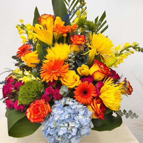 Bright mixed bouquet with roses, gerberas, lilies, and blue hydrangea in a vase