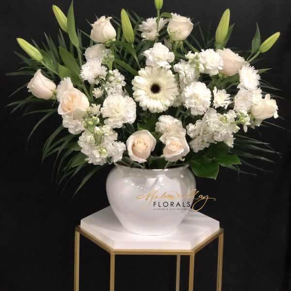 White roses and lilies arranged in a white vase